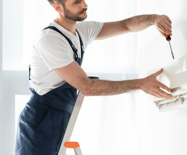 handsome-repairman-standing-on-stepladder-and-fixing-air-conditioner-with-screwdriver.jpg